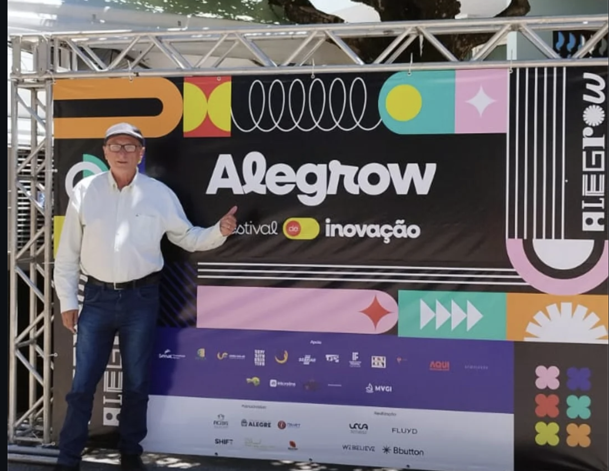 Participante posa em frente ao painel do Alegrow festival de inovação