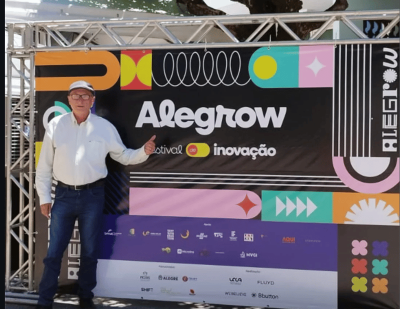 Participante posa em frente ao painel do Alegrow festival de inovação
